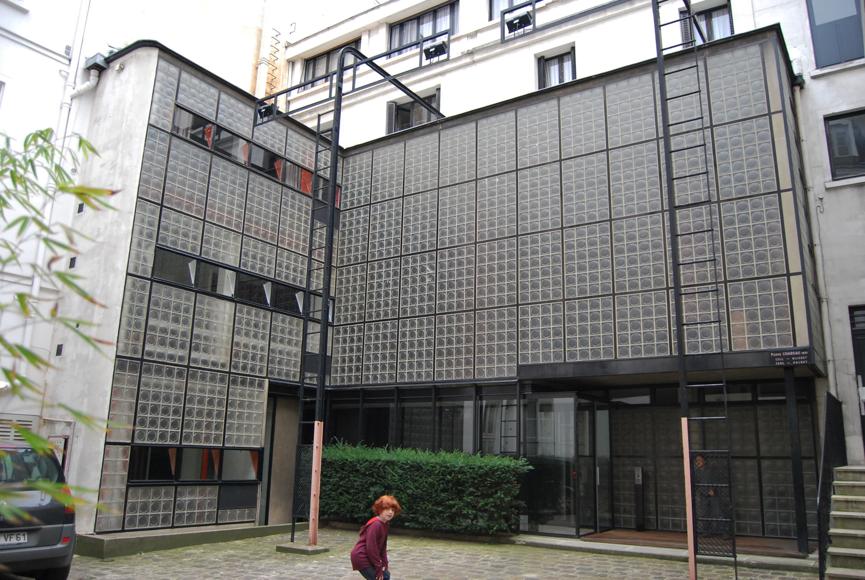 The courtyard facade of the Maison de Verre in Paris: a full-height wall of translucent glass blocks in a steel frame, with slender columns and a glazed ground floor beneath.